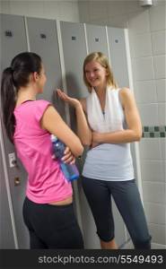 Young fit women chatting in locker room at gym