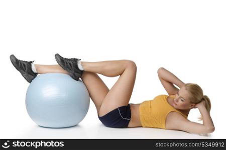 young fitness girl laying on floor doing stretching exercise with a help of big ball