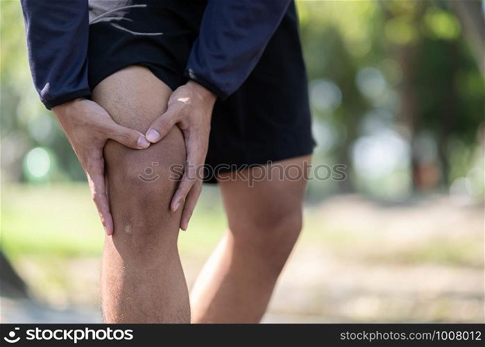Young fitness man holding his sports leg injury, muscle painful during training. Asian runner having calf ache and problem after running and exercise outside in summer