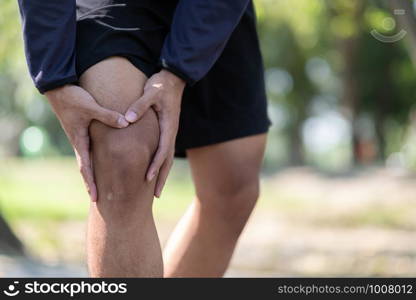 Young fitness man holding his sports leg injury, muscle painful during training. Asian runner having calf ache and problem after running and exercise outside in summer