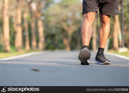 young fitness man legs walking in the park outdoor. male runner running on the road outside. Asian athlete jogging and exercise on footpath in sunlight morning. Sport healthy and wellness concepts