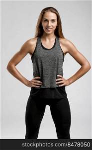 Young fitness woman against a gray background