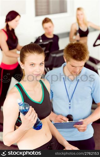 Young fitness woman doing spinning on bicycle with gym instructor