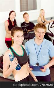 Young fitness woman doing spinning on bicycle with gym instructor