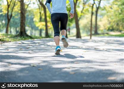 young fitness woman legs walking in the park outdoor, female runner running on the road outside, asian athlete jogging and exercise on footpath in sunlight morning. Sport,healthy and wellness concepts