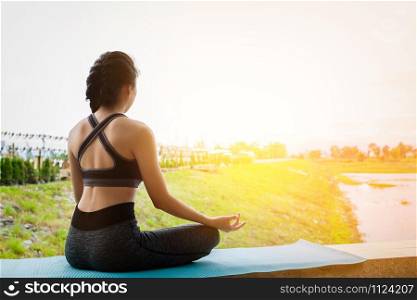 Young fitness woman practicing yoga on the field, healthy lifestyle concept.