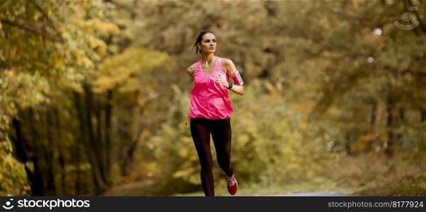 Young fitness woman running at  forest trail in autumn