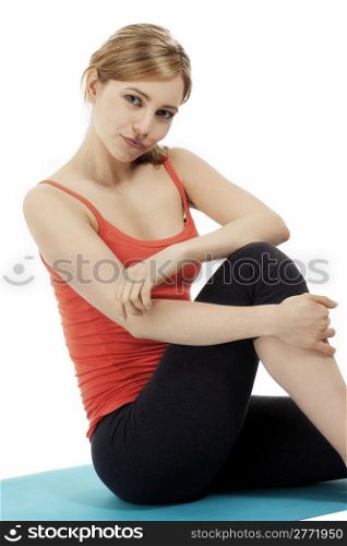 young fitness woman sitting on a blue mat. young fitness woman making a pause sitting on a blue mat on white background