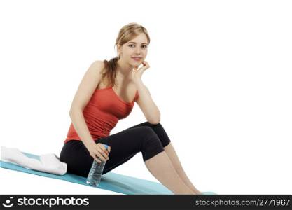 young fitness woman sitting with a bottle of water. young smiling fitness woman sitting with a bottle of water on white background