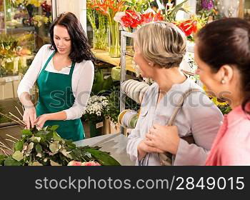 Young florist preparing cut flowers shop buyers bouquet customers