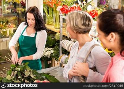 Young florist preparing cut flowers shop buyers bouquet customers