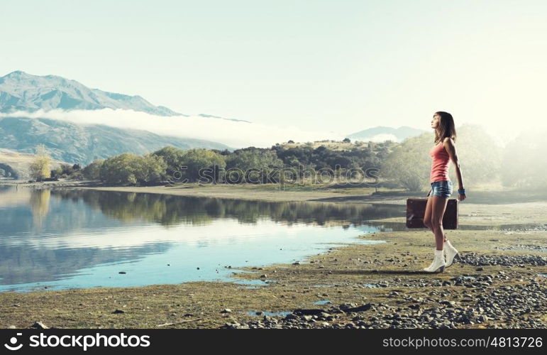 Young free hitchhiker. Traveler woman walking with retro suitcase in hand