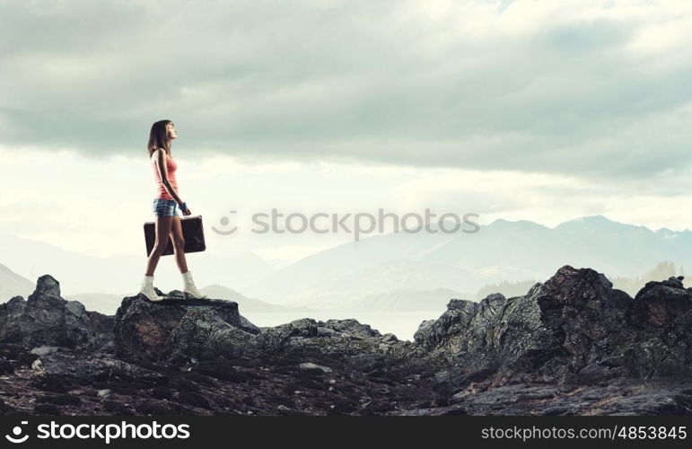 Young free hitchhiker. Traveler woman walking with retro suitcase in hand