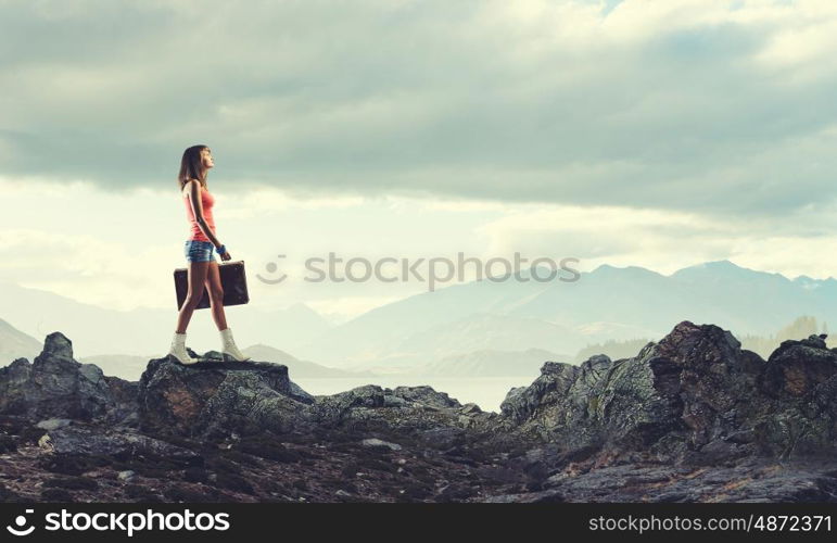 Young free hitchhiker. Traveler woman walking with retro suitcase in hand