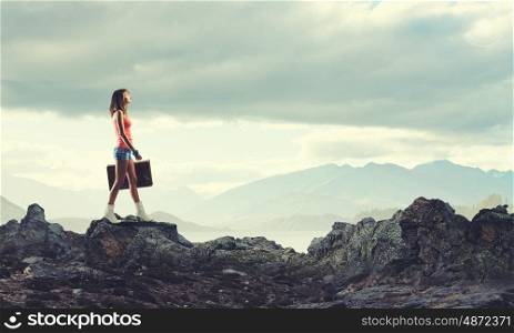 Young free hitchhiker. Traveler woman walking with retro suitcase in hand