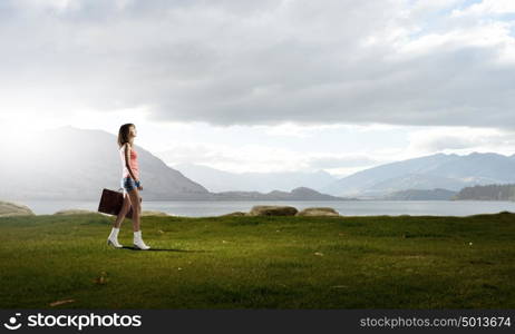 Young free hitchhiker. Traveler woman walking with retro suitcase in hand