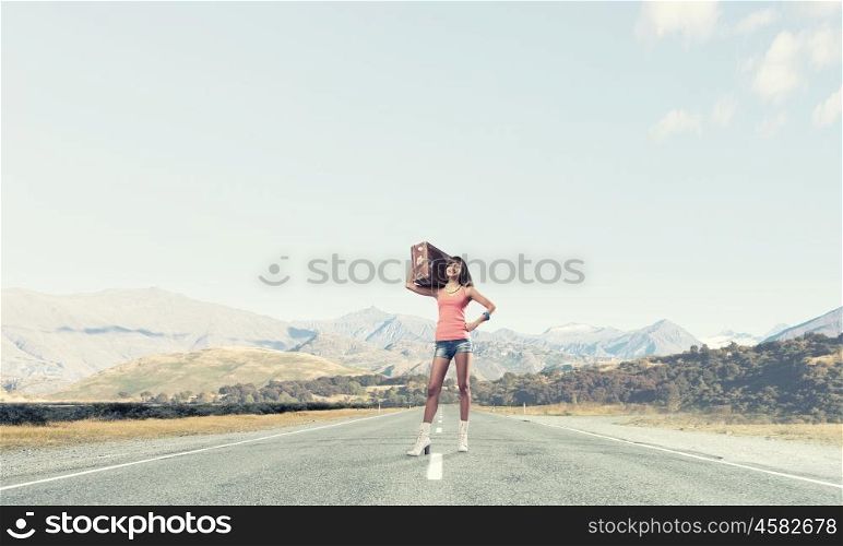 Young free hitchhiker. Traveler woman with retro suitcase waiting for car