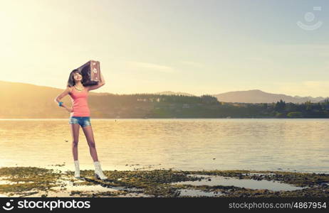 Young free hitchhiker. Traveler woman with retro suitcase waiting for car