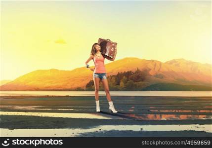 Young free hitchhiker. Traveler woman with retro suitcase waiting for car