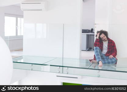 young freelancer in bathrobe working from home using laptop computer while sitting on floor