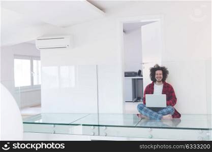 young freelancer in bathrobe working from home using laptop computer while sitting on floor
