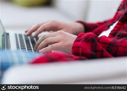 young freelancer in bathrobe working from home using laptop computer while sitting on sofa