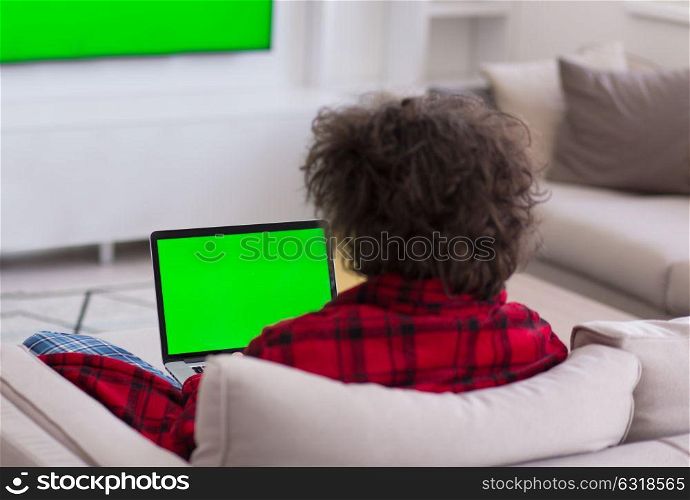 young freelancer in bathrobe working from home using laptop computer while sitting on sofa