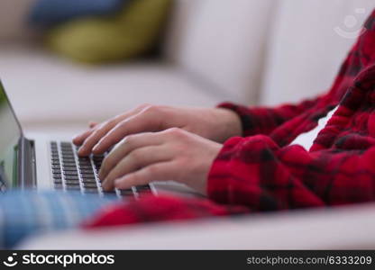 young freelancer in bathrobe working from home using laptop computer while sitting on sofa