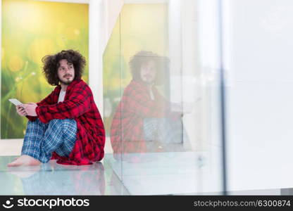 young freelancer in bathrobe working from home using tablet computer