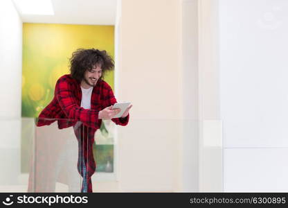 young freelancer in bathrobe working from home using tablet computer