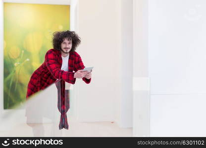 young freelancer in bathrobe working from home using tablet computer