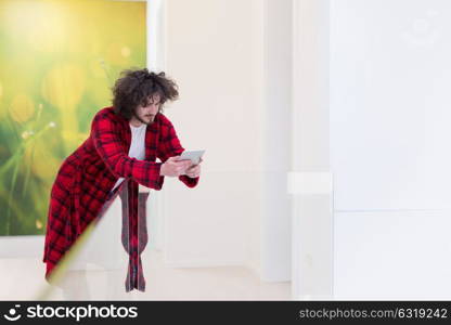 young freelancer in bathrobe working from home using tablet computer