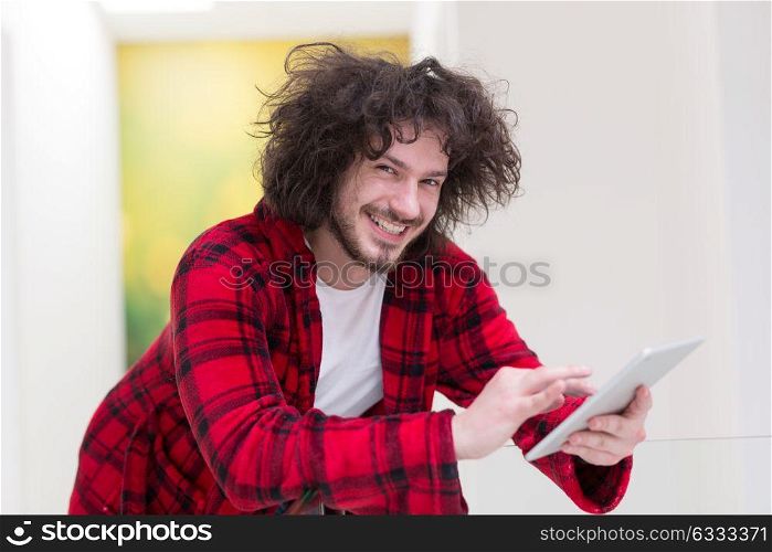 young freelancer in bathrobe working from home using tablet computer