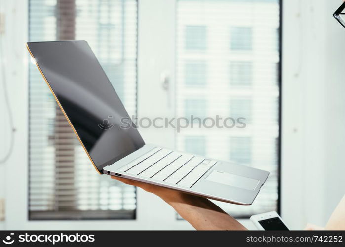 Young freelancer in black shirts holds up a very thin, elegant Ultrabook