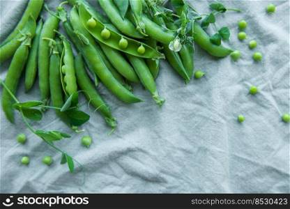 Young fresh juicy pods of green peas on a green textile background. Healthy organic food. 