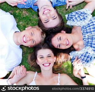 Young friends forming a circle making park as their bed and holding each others hands