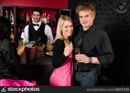 Young friends toasting with champagne in front of the bar