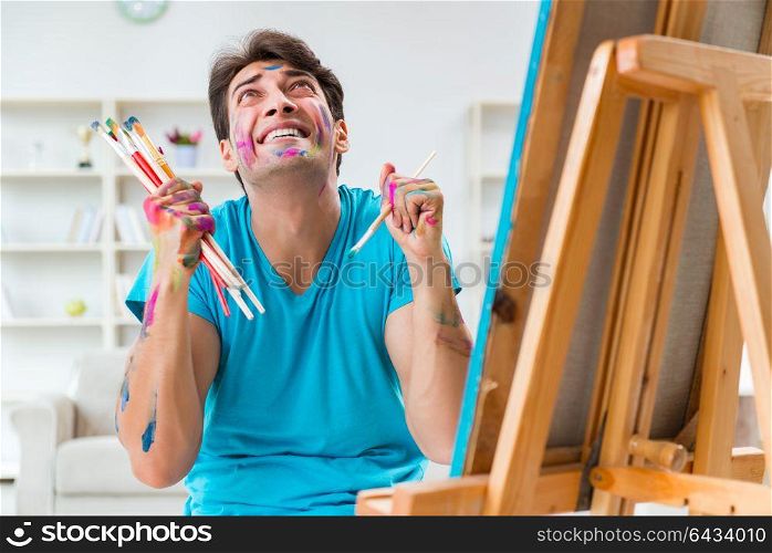 Young funny artist working on new painting in his studio