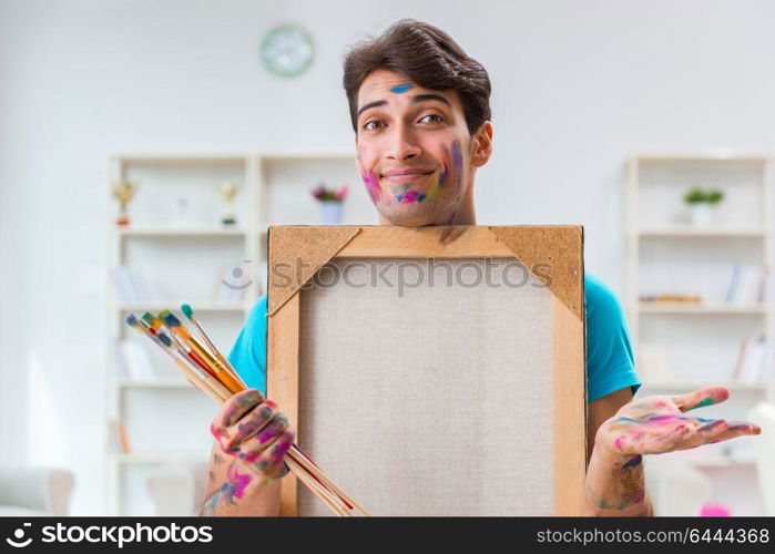 Young funny artist working on new painting in his studio