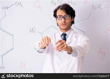 Young funny chemist in front of white board 