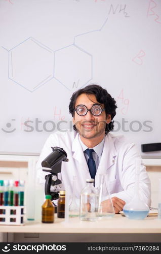 Young funny chemist in front of white board 