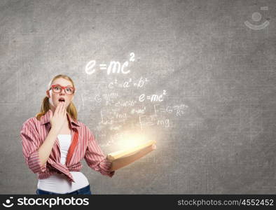 Young funny girl with opened book in hands. Girl excited with book