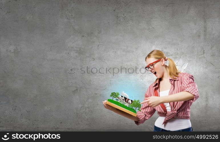 Young funny girl with opened book in hands. Girl excited with book