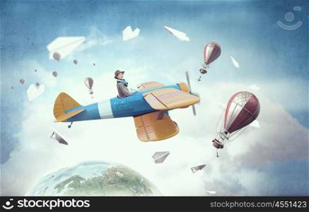 Young funny woman flying in air in retro airplane. Elements of this image are furnished by NASA. Girl flying old plane