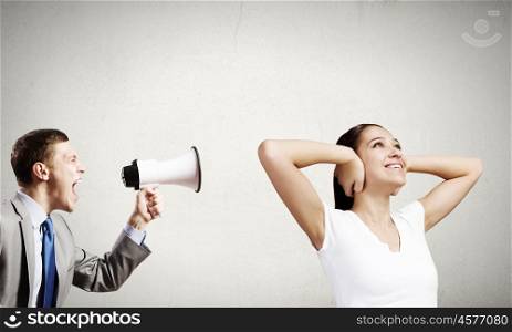 Young furious man screaming agressively in megaphone. Agressive management
