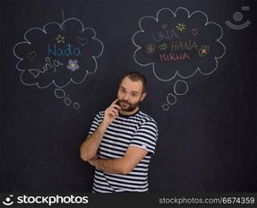 young future father thinking in front of black chalkboard. young future father thinking about names for his unborn baby to writing them on a black chalkboard