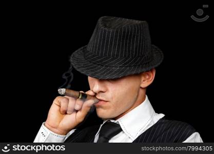young gangster with hat smoking cigar, studio shot