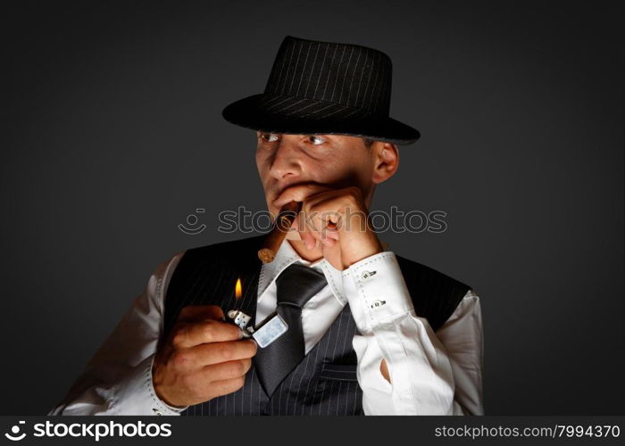 young gangster with hat smoking cigar, studio shot