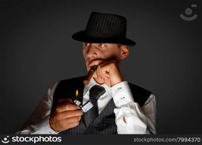young gangster with hat smoking cigar, studio shot