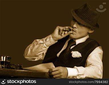 young gangster with hat smoking cigar, studio shot, sepia toning